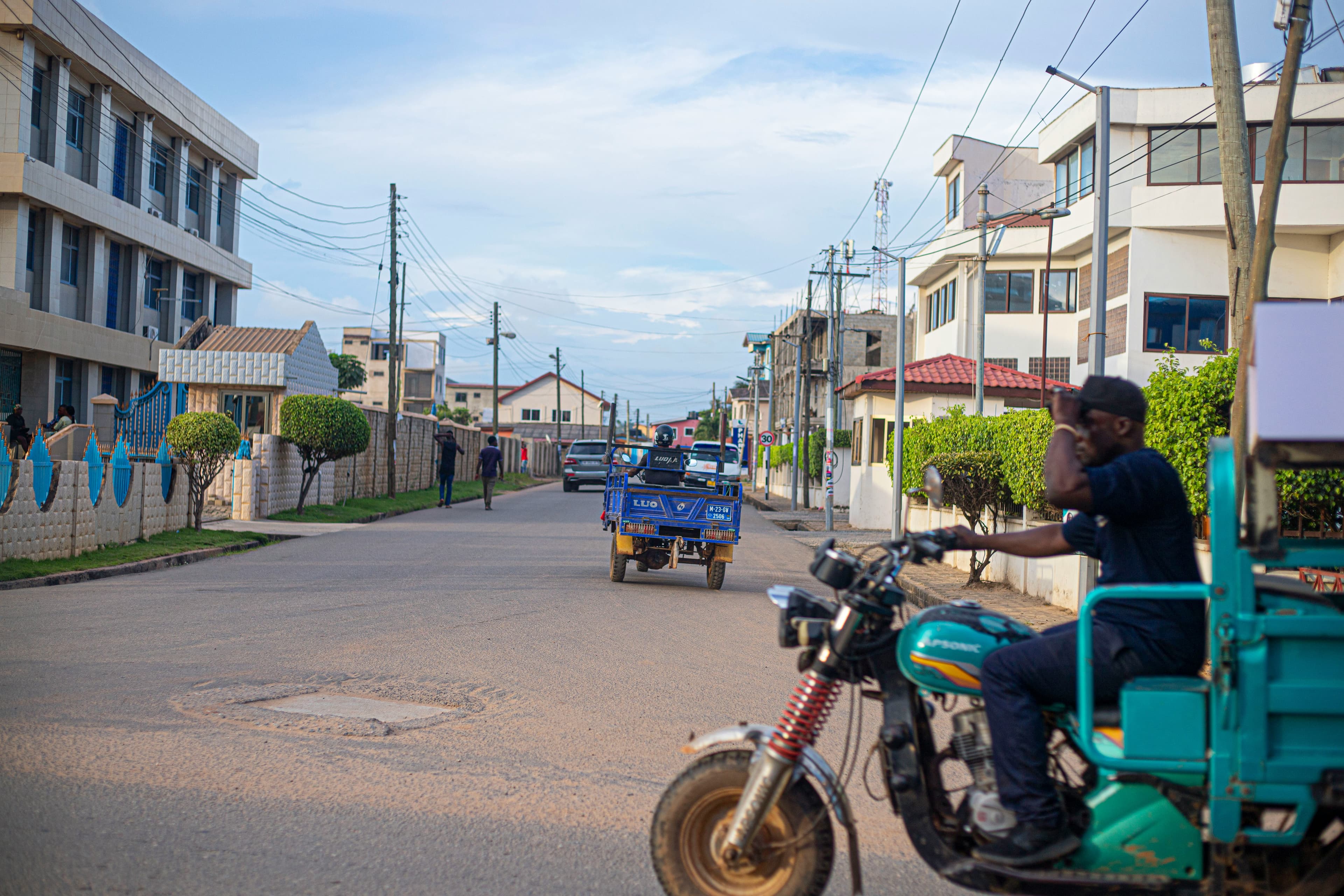 A street in Ghana with a motorcycle and tricycle taxi